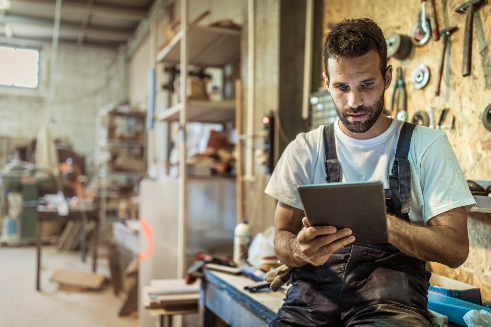 Un bărbat într-un atelier folosește consultantul pentru produse STIHL pe o tabletă