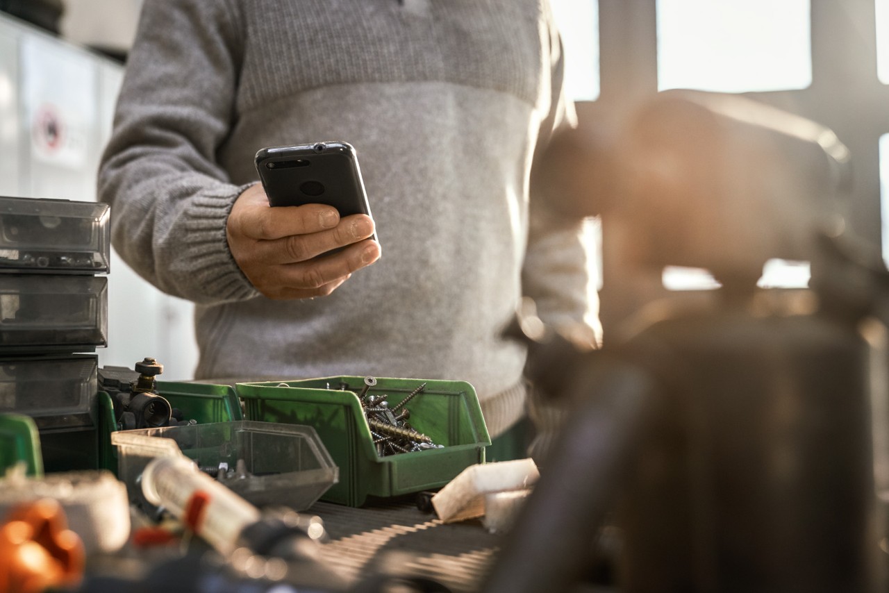Persoană cu un smartphone într-un atelier