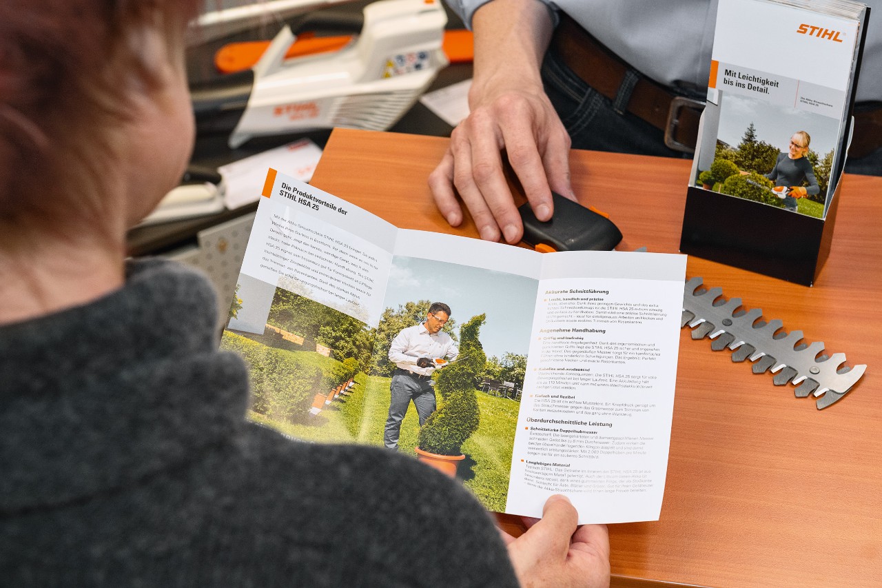 O persoană se uită la avantajele produsului STIHL HSA 25 într-o broșură