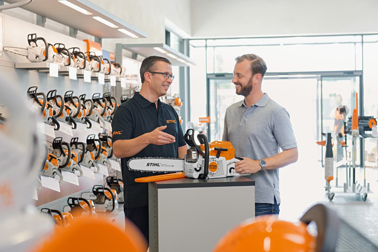 Distribuitorul STIHL consiliază un bărbat la cumpărarea unui motoferăstrău STIHL