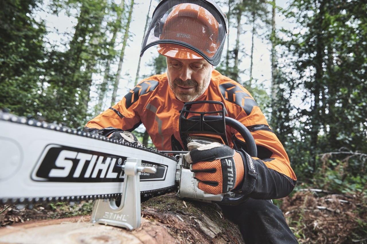 Un bărbat îmbrăcat în echipament de protecție lucrează cu un motoferăstrău STIHL în pădure