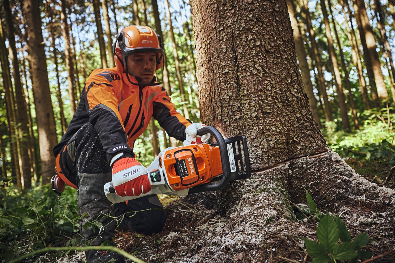 Un bărbat în echipament de protecție STIHL taie un butuc