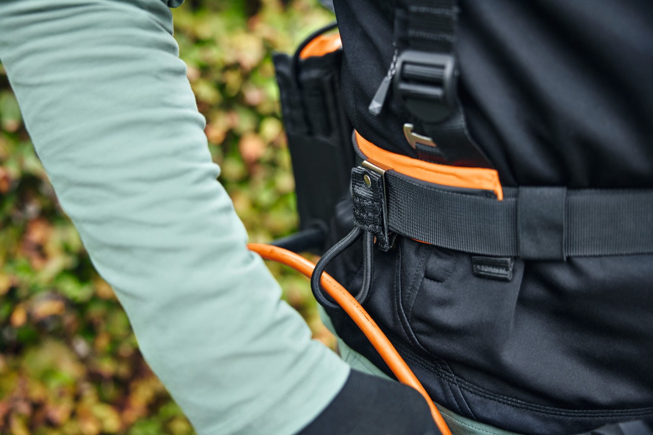 O persoană poartă sistemul modular de centuri STIHL ADVANCE X-Flex cu o geantă pentru acumulator cu cablu de conexiune și ghidaj de cablu