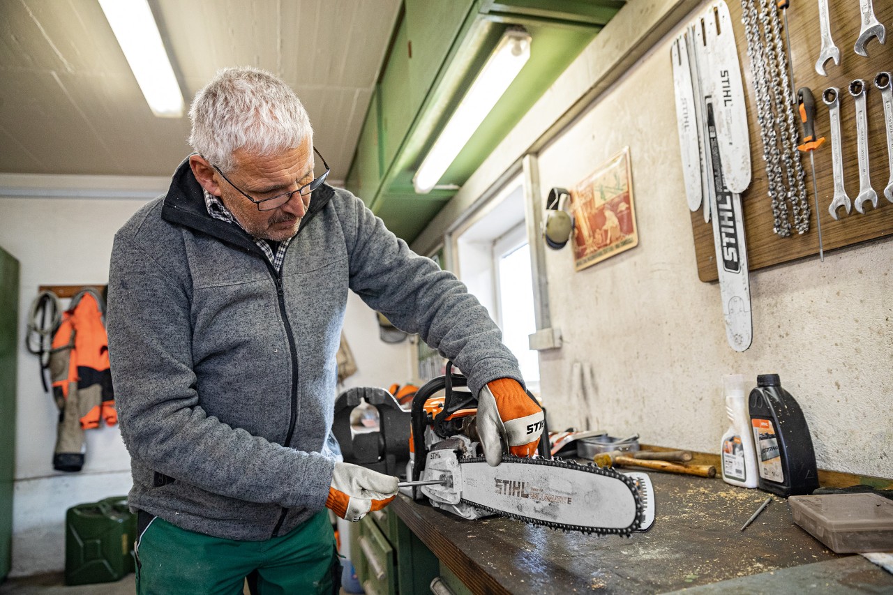 Un bărbat tensionează lanțul unui motoferăstrău STIHL