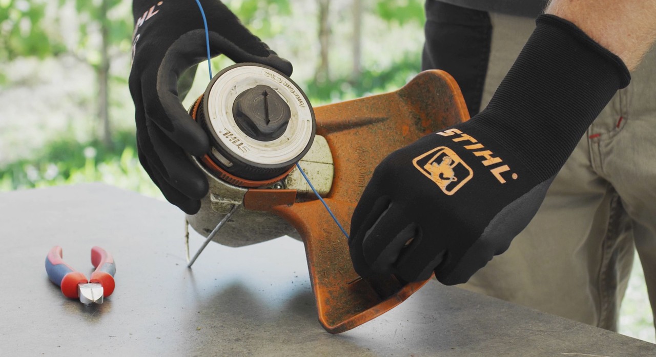 O persoană înfășoară firul cositor al unei motocoase cu acumulator STIHL FSA 57