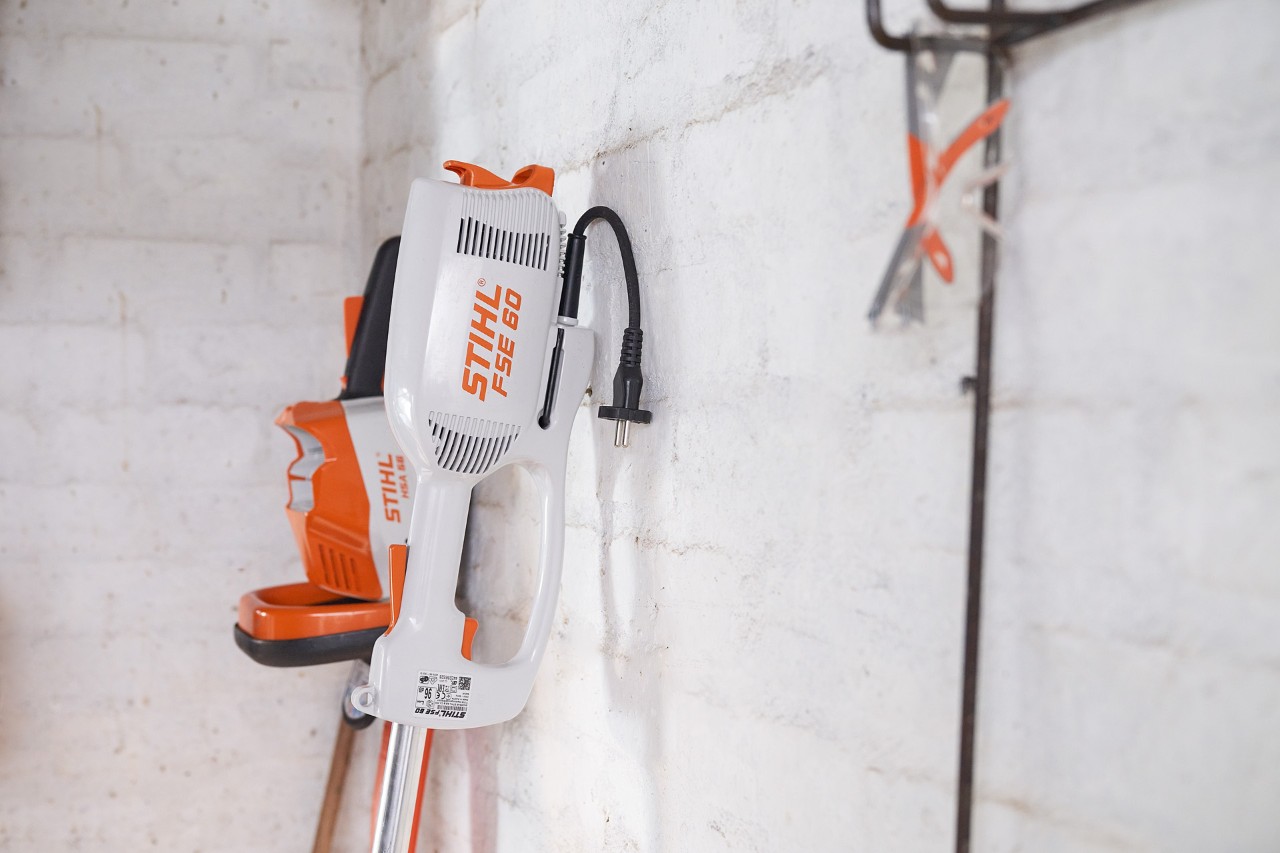 A STIHL FSE 60 electric brushcutter being stored in a garage