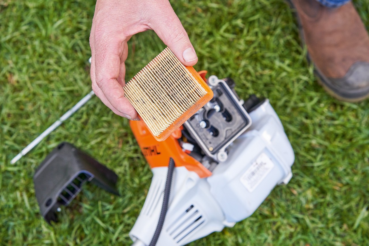 O persoană scoate filtrul de aer al unei motocoase STIHL pentru a-l curăța 