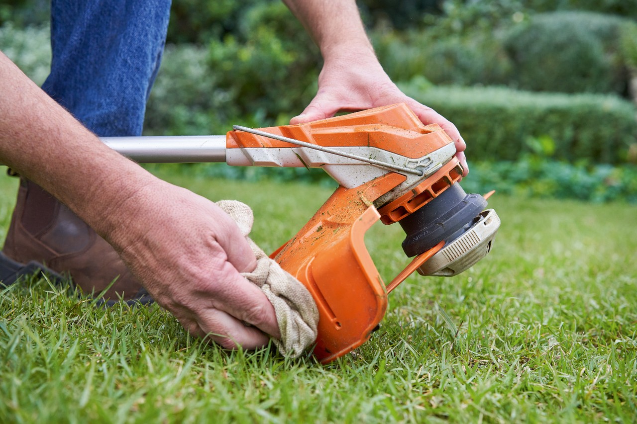 O persoană curăță apărătoarea unei motocoase STIHL cu o lavetă umedă