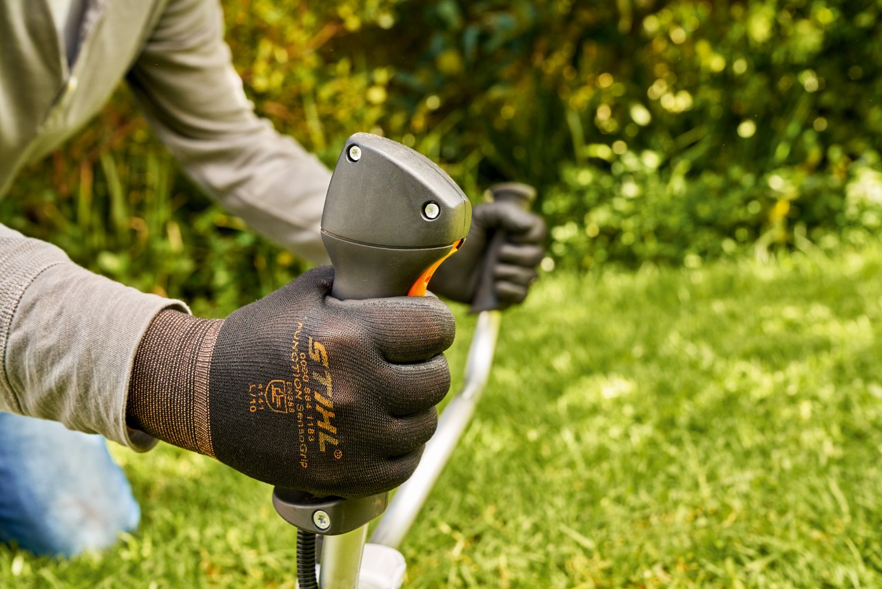 Un bărbat pornește motorul motocoasei pe benzină STIHL FS 91 pentru scurt timp