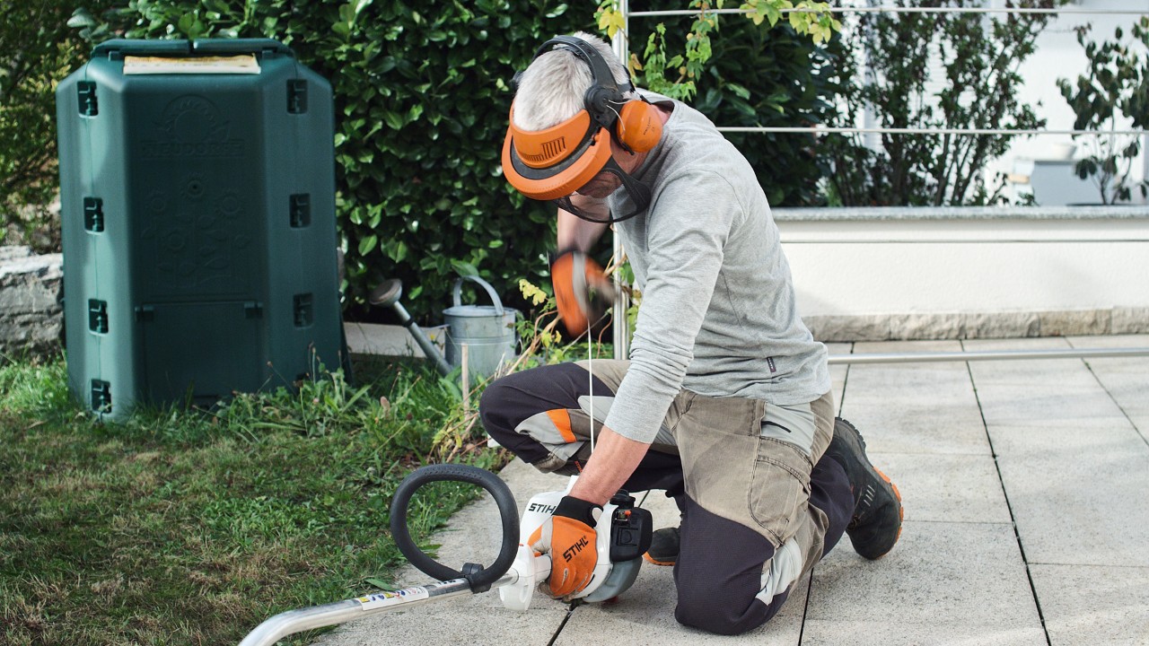 O persoană care poartă îmbrăcăminte de protecție trage șnurul demaror al motocoasei pe benzină STIHL FS 38