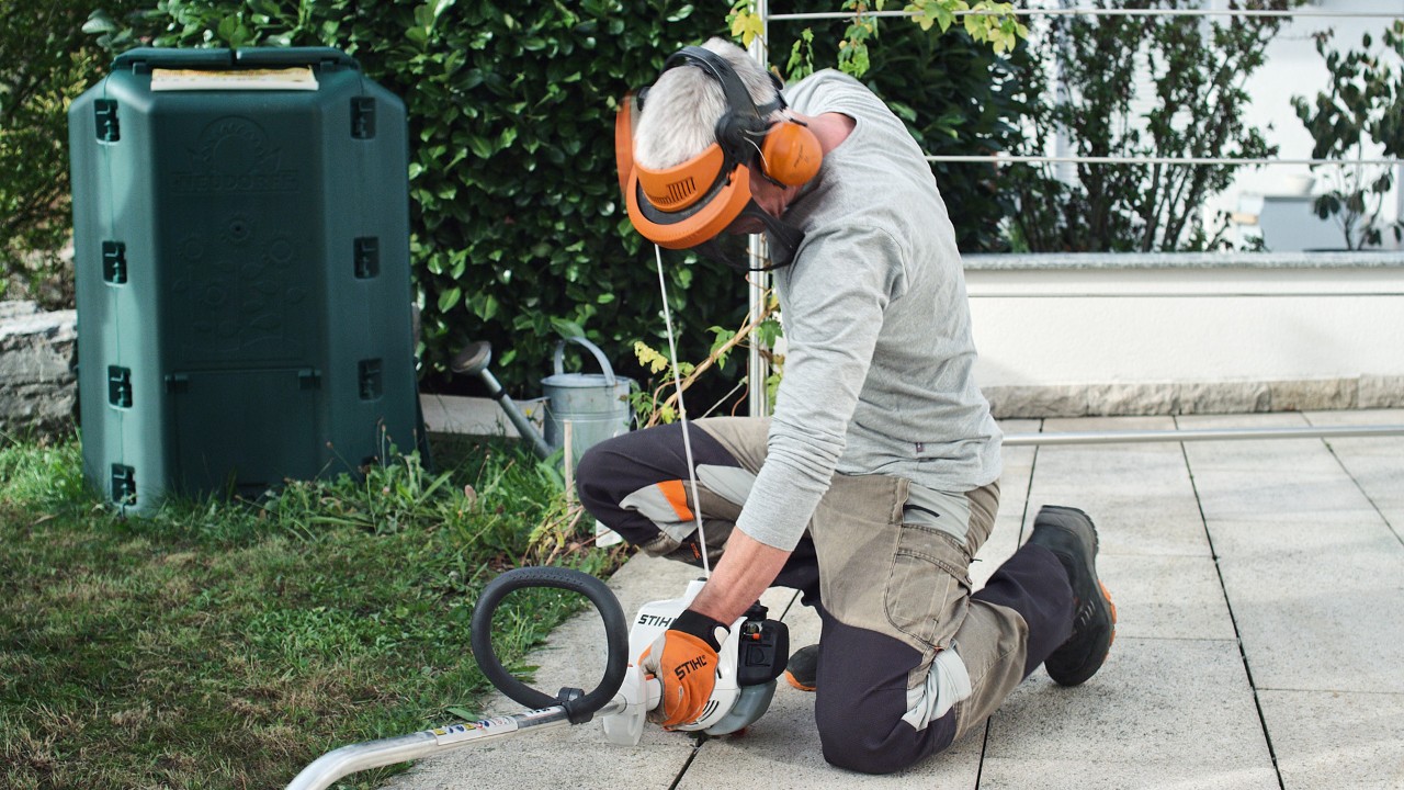 O persoană care poartă îmbrăcăminte de protecție trage din nou de șnurul demaror al motocoasei pe benzină STIHL FS 38