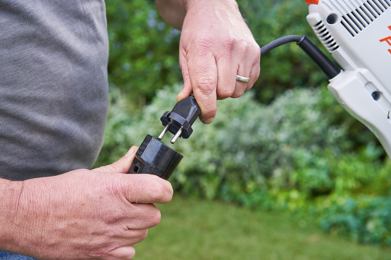 Un bărbat cu mănuși de protecție acționează maneta de acționare a motocoasei electrice STIHL FSE 60 pentru a o porni