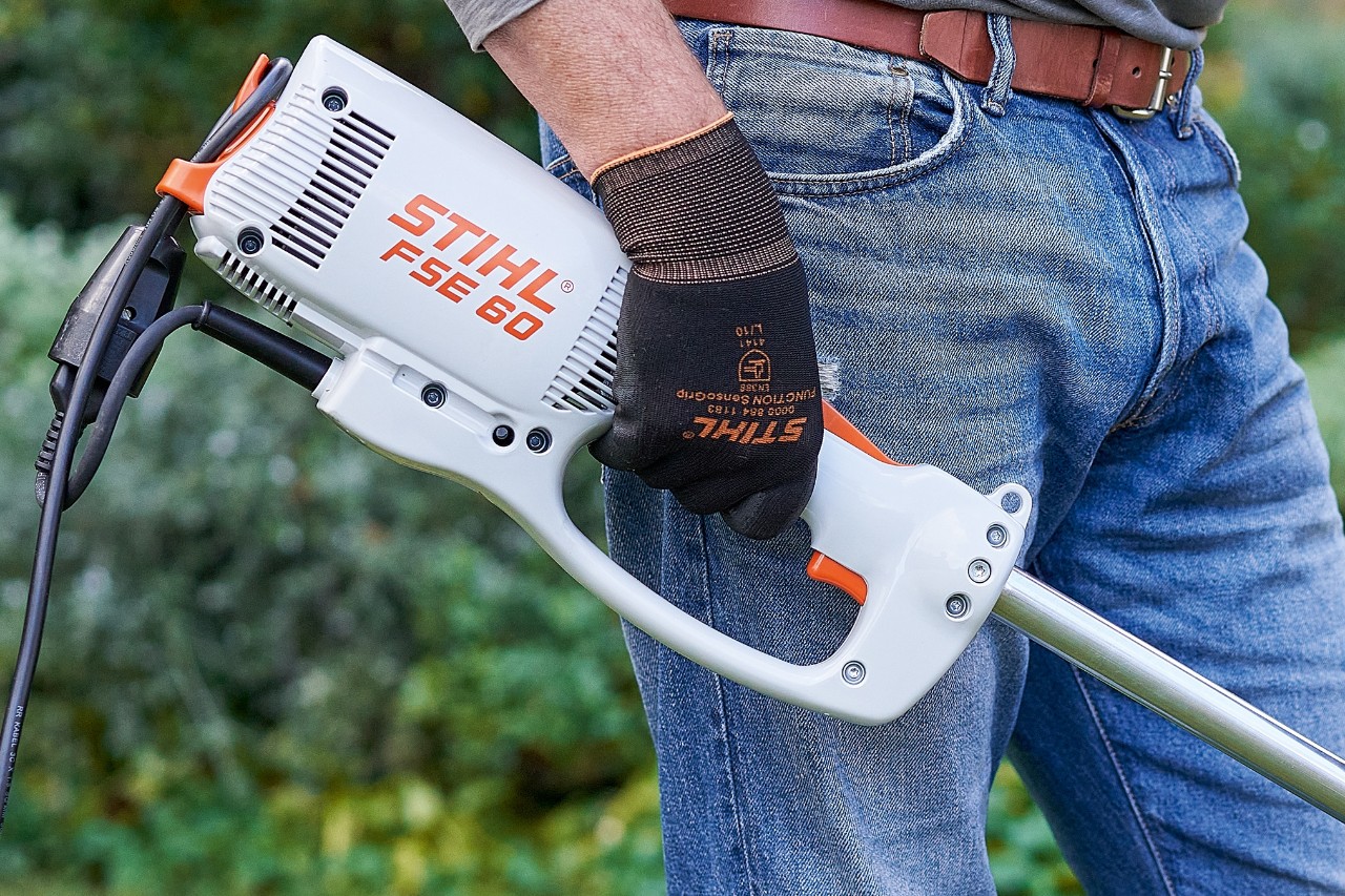 Un bărbat acționează comutatorul pentru a opri motocoasa electrică STIHL FSE 60.