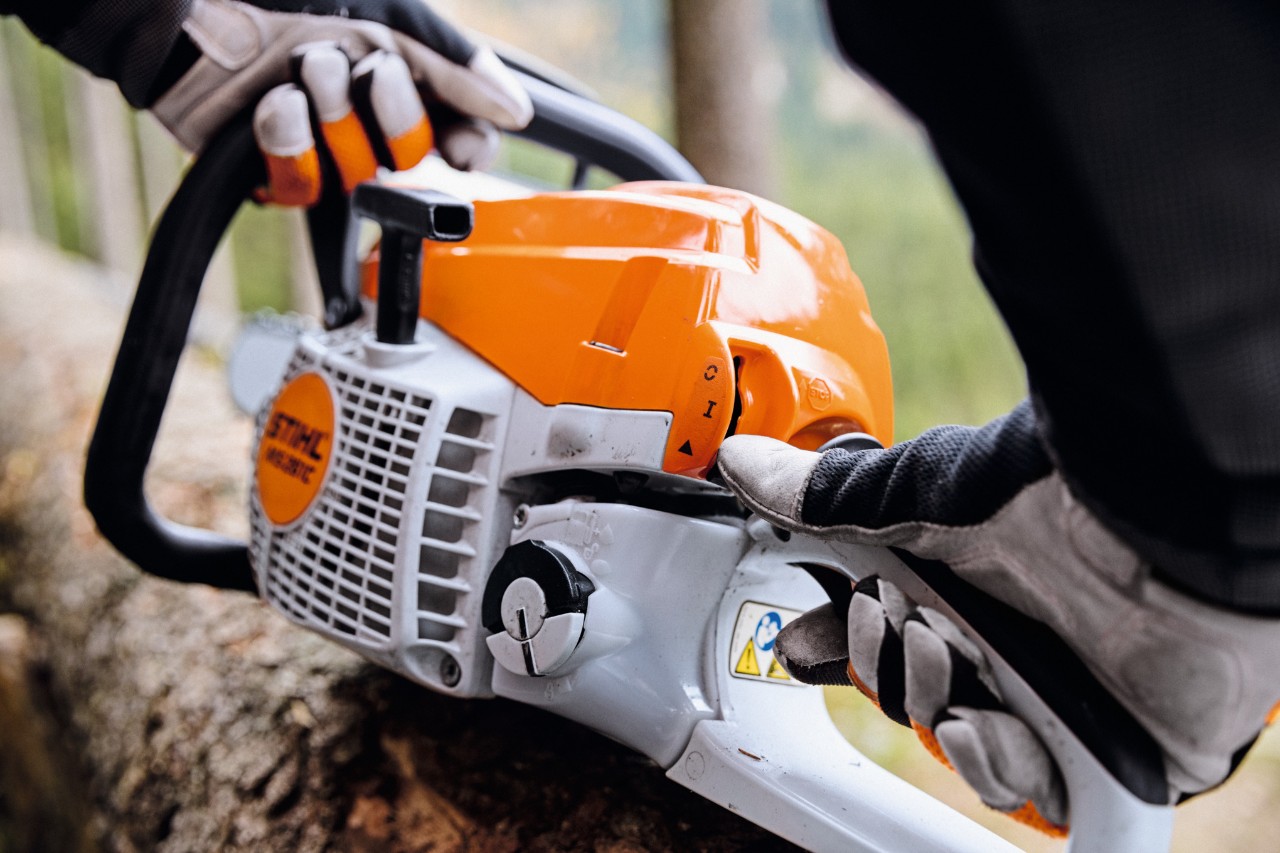 Prim-plan al unui motoferăstrău pe benzină STIHL MS 261 C-M care este pornit de o persoană care poartă mănuși de protecție