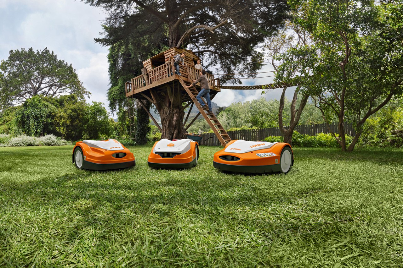Diferiți roboți de tuns iarba STIHL iMOW® pe gazon verde în grădină