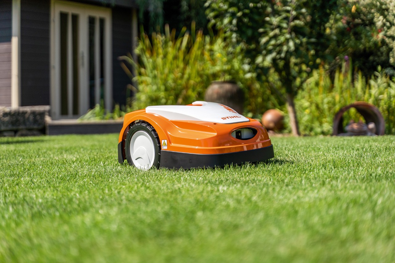 Robotul de tuns iarba STIHL iMOW® RMI 422 pe gazon verde în fața unei case 