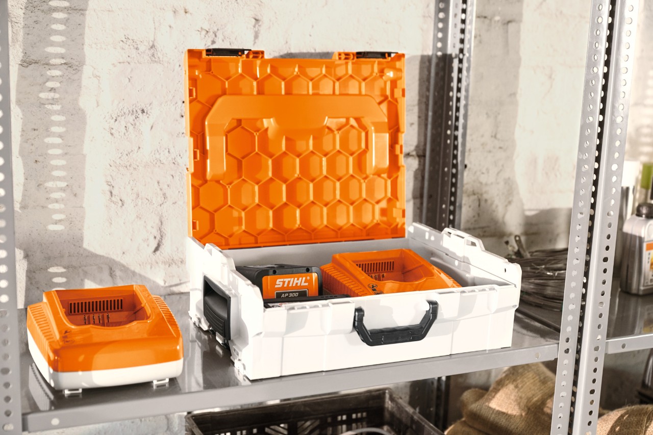 Cutie de acumulatori STIHL cu acumulatorii STIHL pe un raft din atelier  